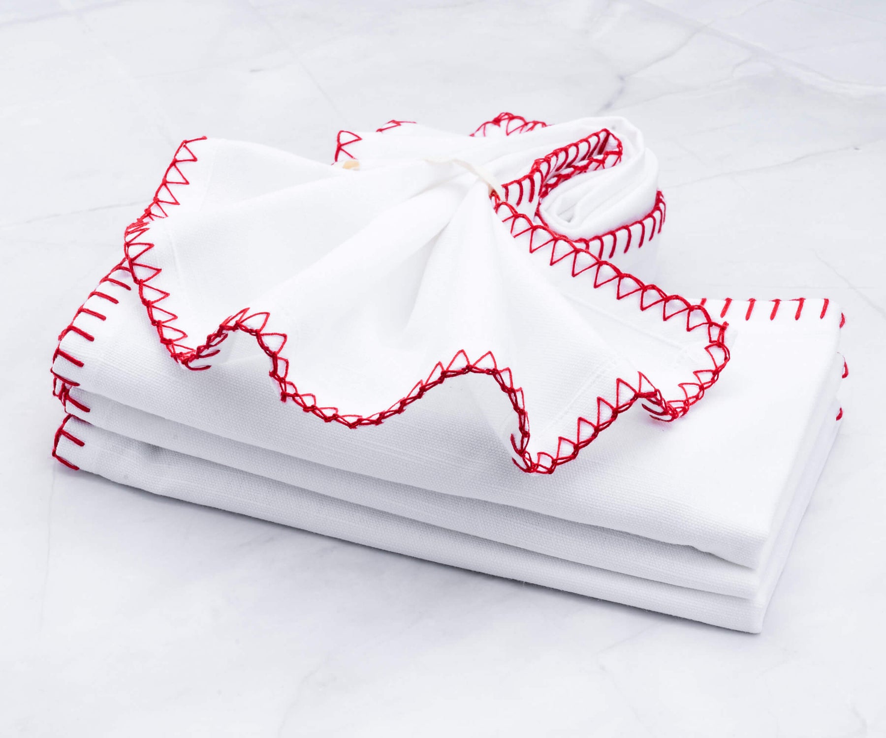 Pile of shell edge cloth napkins with red detailing