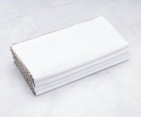 White linen wedding napkins with gold shell edging presented on a table