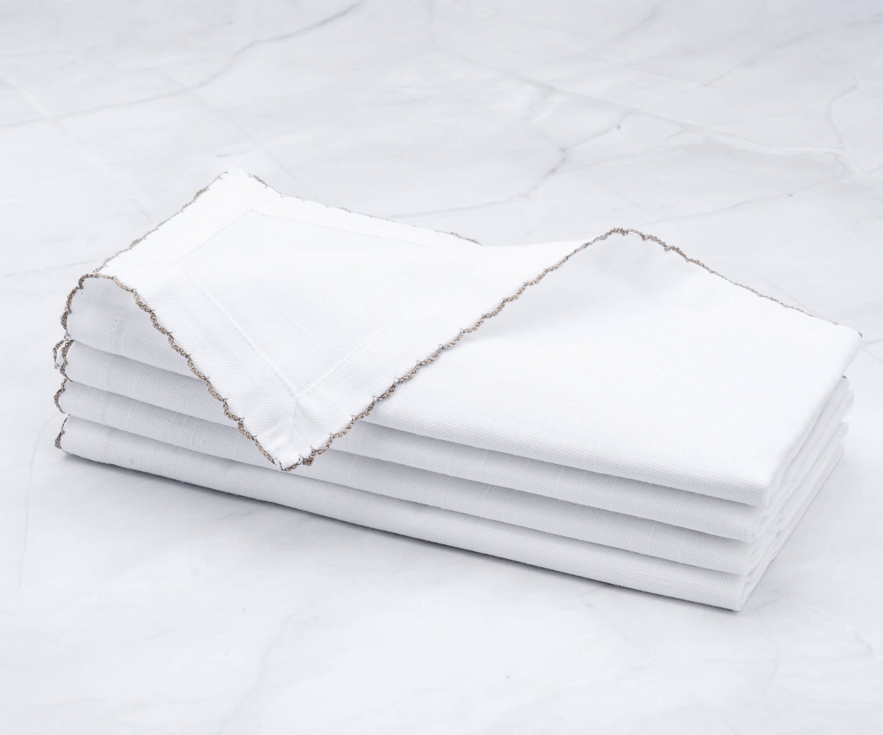 Quartet of shell edge napkins elegantly folded on marble