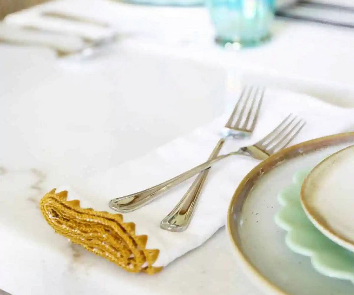 Wedding table setting with shell edge napkin and silver fork on white linen