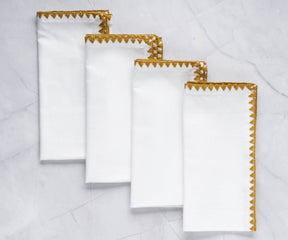 Quartet of white wedding napkins with shell edge and gold detailing