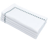A stack of white cotton cloth napkins with green snowflake embroidery along the edges.
