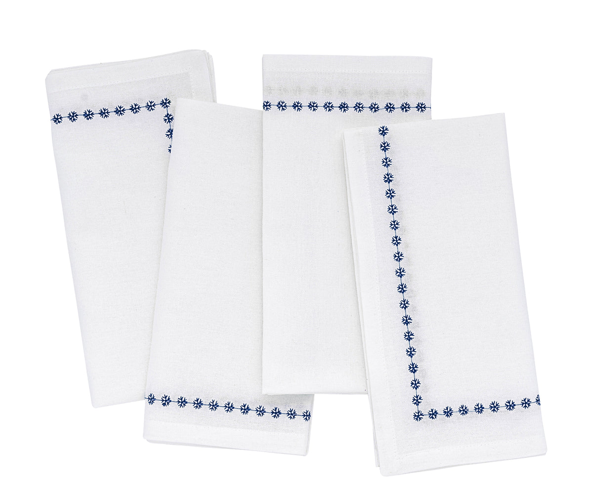 Set of four white napkins with blue floral embroidery on a white background