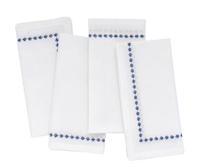 Set of four white napkins with blue floral embroidery on a white background
