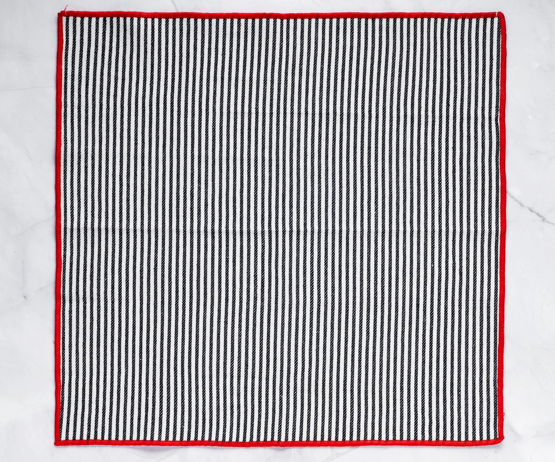 black cotton napkin showcasing red border stitching and fine texture.