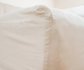 White cotton fitted sheet displayed on a bed