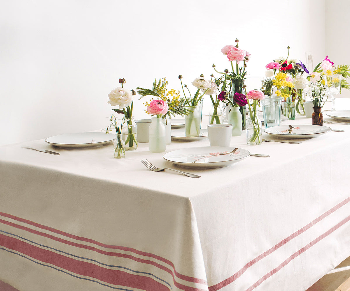 Table decorated with flowers and vases on a French tablecloth.Cotton Tablecloth for Farmhouse Charm. 