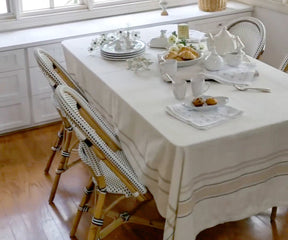 Dining room table with a rectangle tablecloth in red and white stripes and white chairs