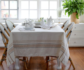Dining room table with a French tablecloth in red and white stripes and white chairs