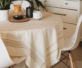 A French tablecloth displayed on a table with a white chair and coffee pot