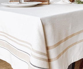 Table adorned with a French tablecloth in white and brown stripes and Classic Farmhouse Rectangle Tablecloth in Cotton.