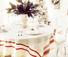 Christmas dinner setting on a French tablecloth with a Christmas tree in the background