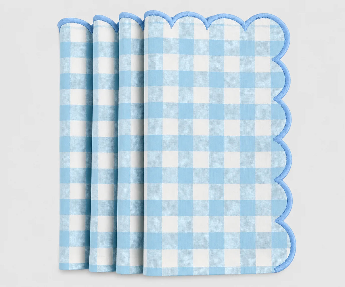 A stack of light blue and white gingham check paper napkins with scalloped edges, shown on a clean white background.