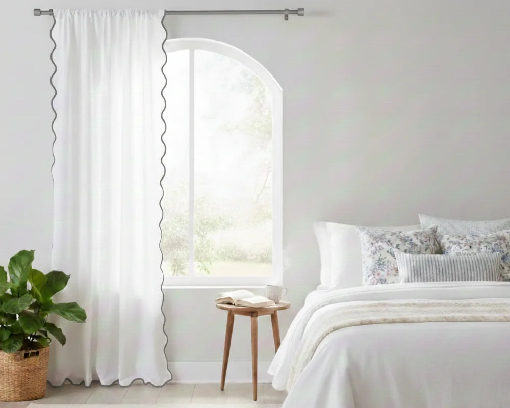 White curtain with gray wavy side trim in a bedroom setting