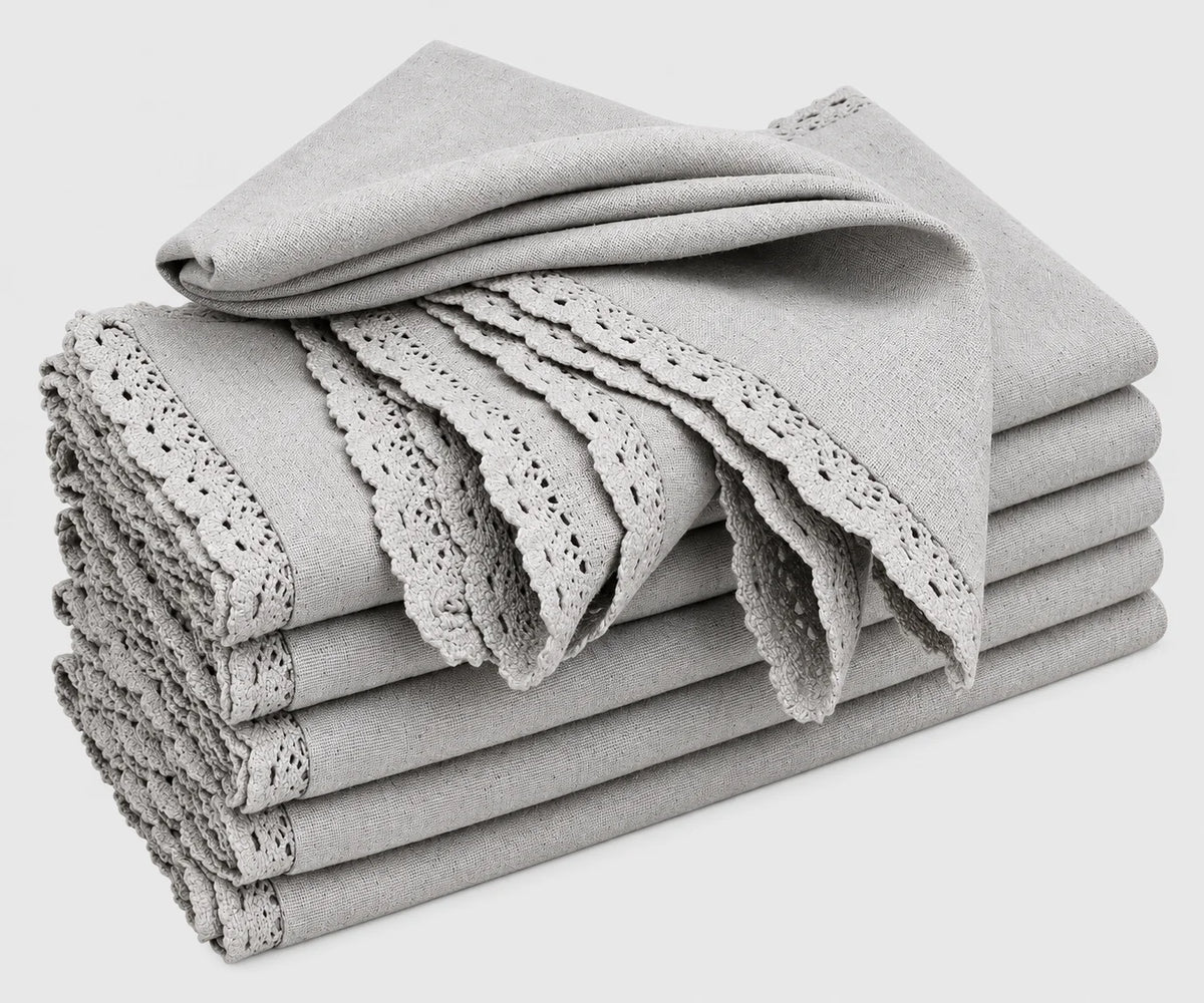 A stack of folded gray cotton cloth napkins featuring delicate lace trim and cutwork edges