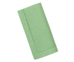 Sage green linen napkins with elegant hemstitched edges, neatly folded on a rustic wooden table.

