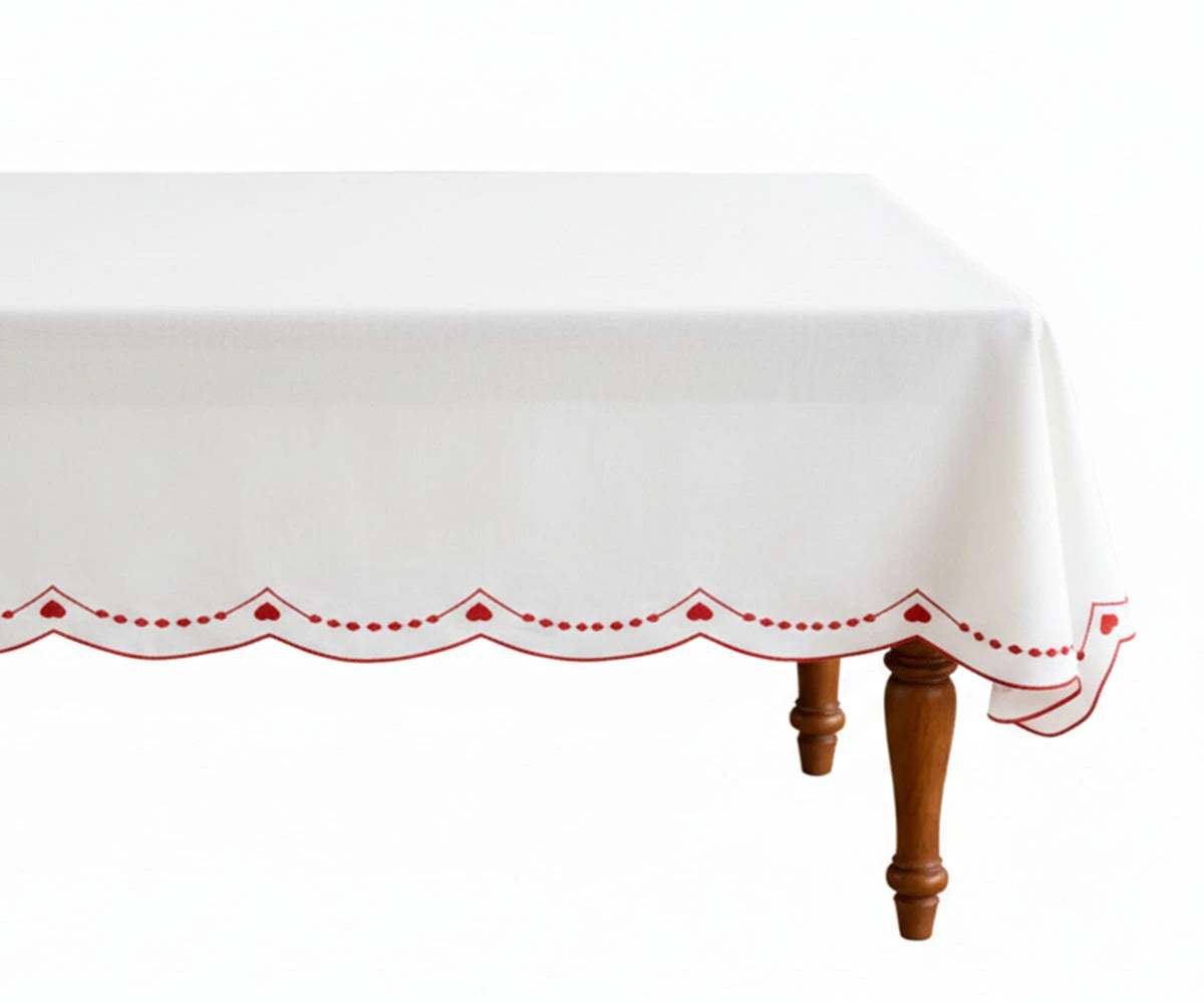 White tablecloth with red scalloped embroidered border on dining table