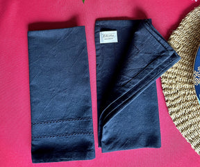 Two navy cloth dinner napkins displayed on a dining table napkins
