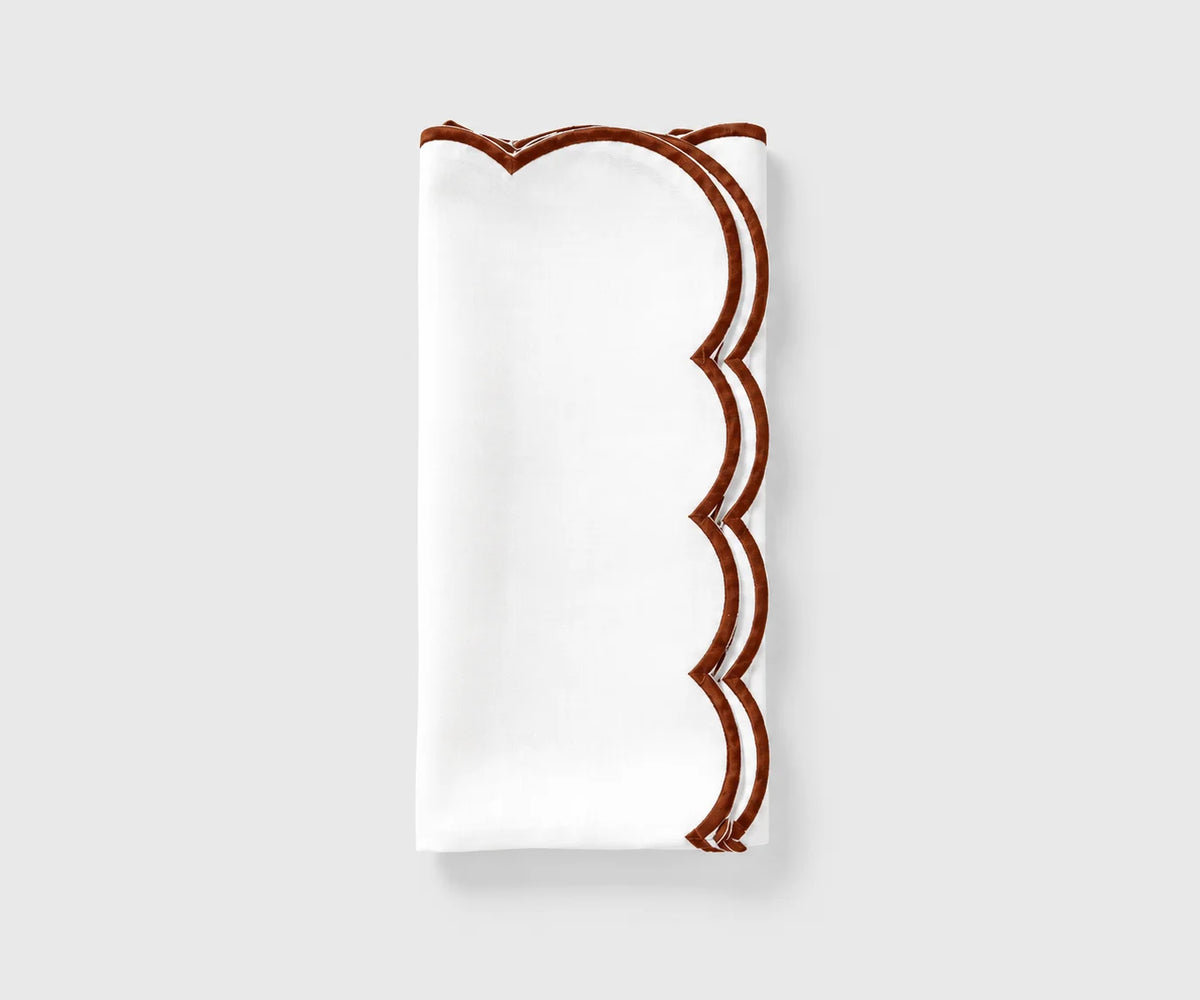 White and chocolate scalloped cloth napkin folded on a white background