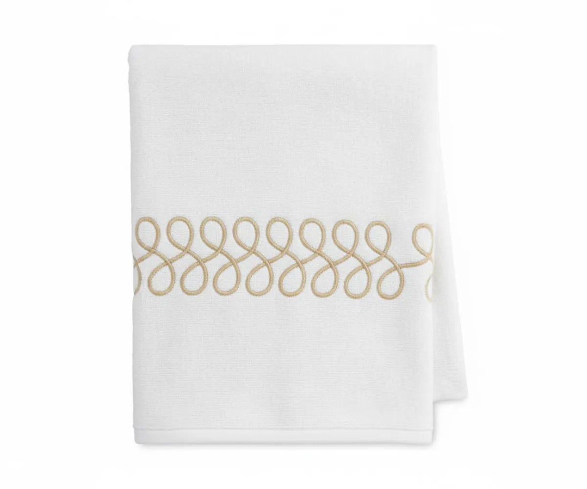 High-quality beige and white bath towels showing embroidered pattern and plush texture