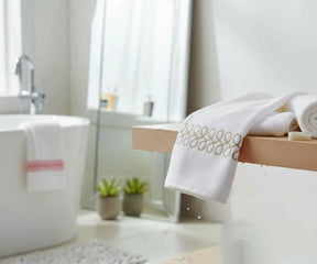Beige and white embroidered bath towels stacked neatly for a luxury spa look