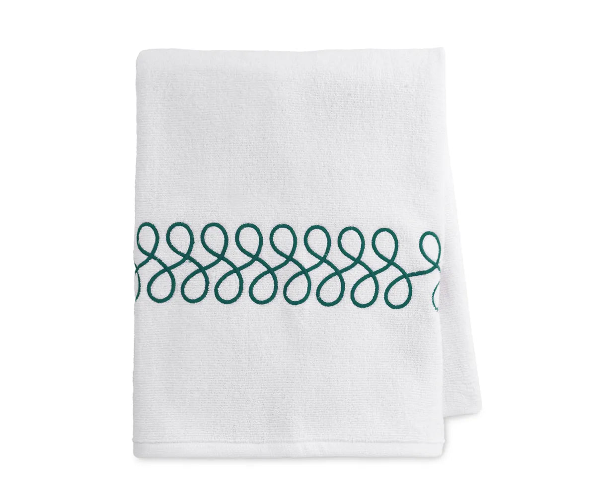Embroidered white and green bath towels neatly folded, showcasing luxury cotton texture