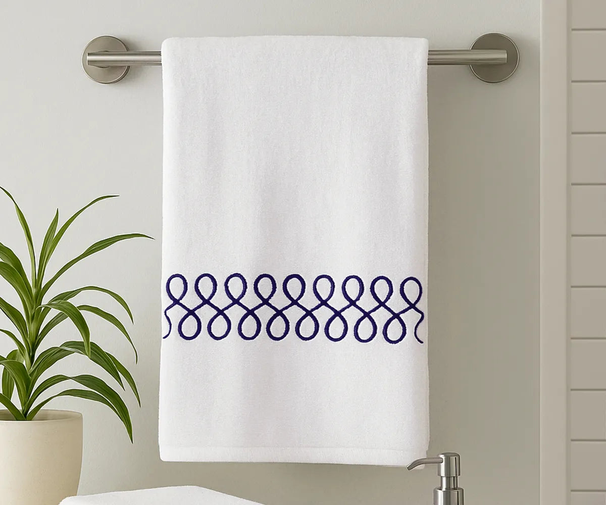 White cotton bath towel with elegant navy embroidery displayed in a modern bathroom