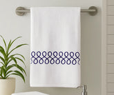 White cotton bath towel with elegant navy embroidery displayed in a modern bathroom