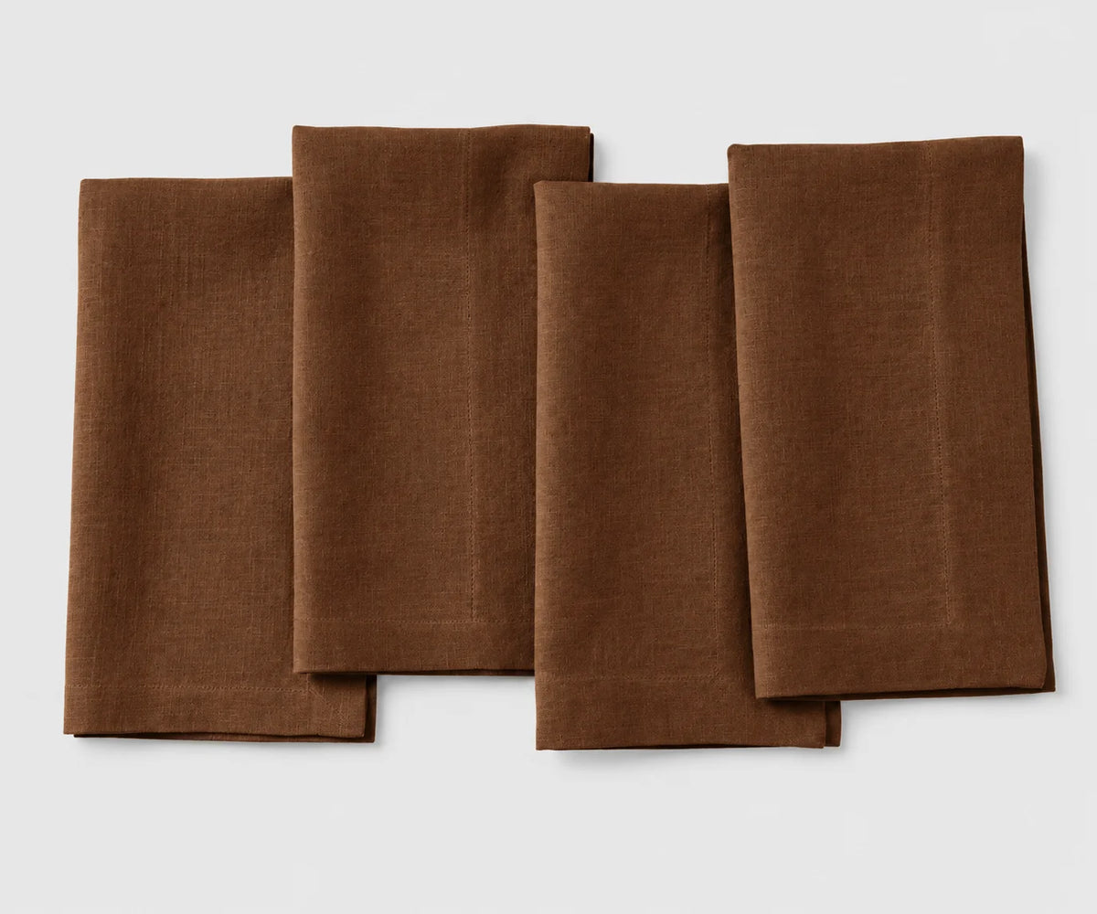 Set of four folded chocolate brown linen cloth dinner napkins for weddings and dining table settings