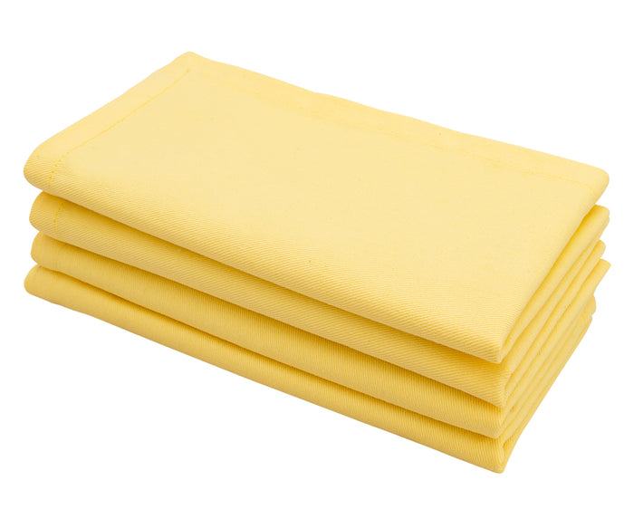 Lemon yellow cotton cloth dinner napkin neatly folded on a dining table.