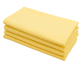 Lemon yellow cotton cloth dinner napkin neatly folded on a dining table.