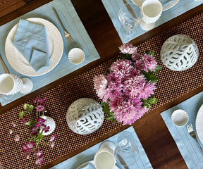 Dining table prepared with a placemat, floral centerpiece, and elegant napkin