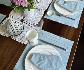 Chic table presentation with Cloth Dinner Napkins on blue placemats beside spotless white plates