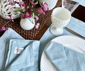 Dining table showcasing a white plate, blue cloth napkin, and a vase with flowers