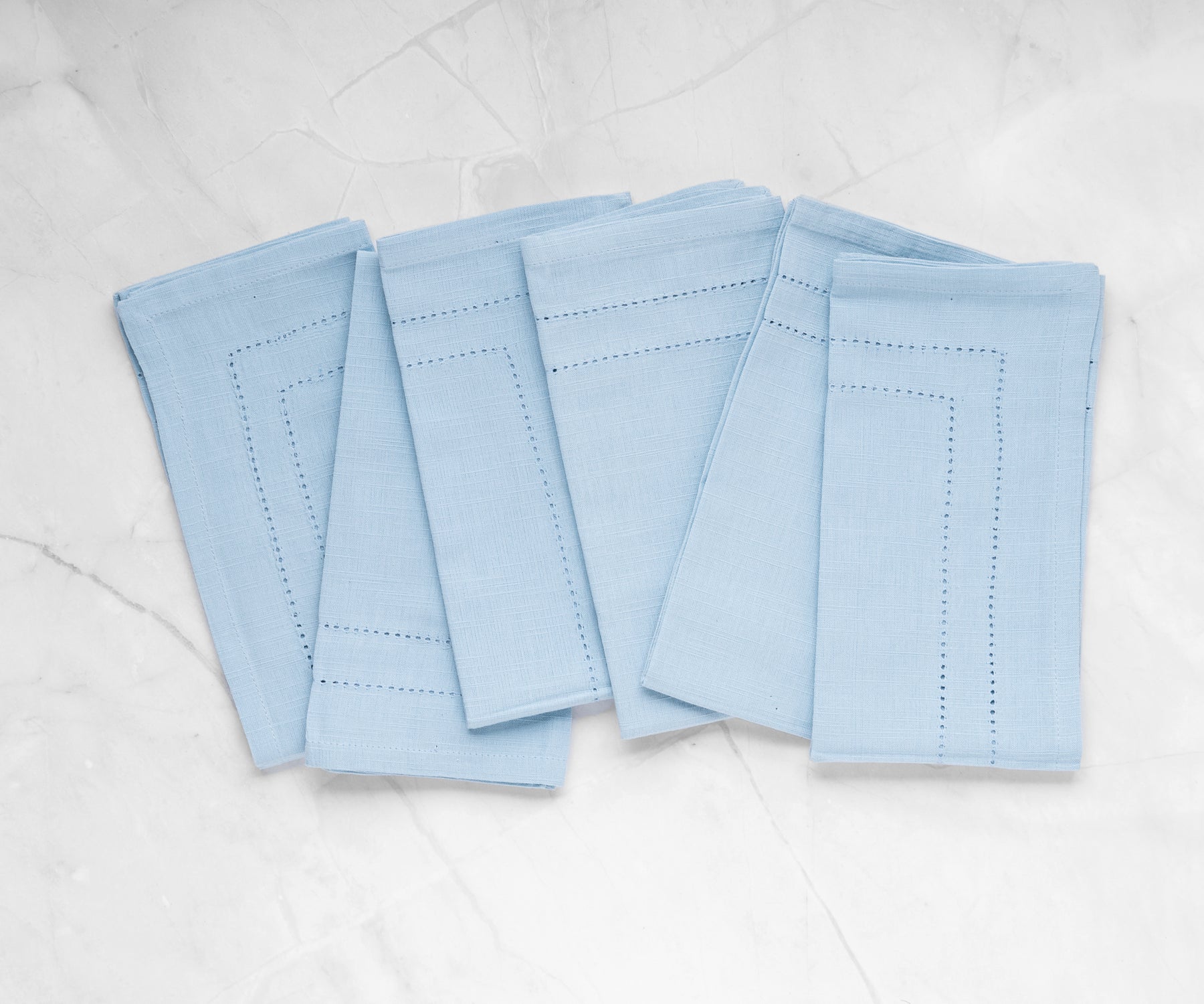 Light blue dinner napkins featuring an elegant hemstitch design in durable linen.
