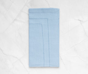 Close-up of a Cloth Dinner Napkin in blue with a delicate white line accent