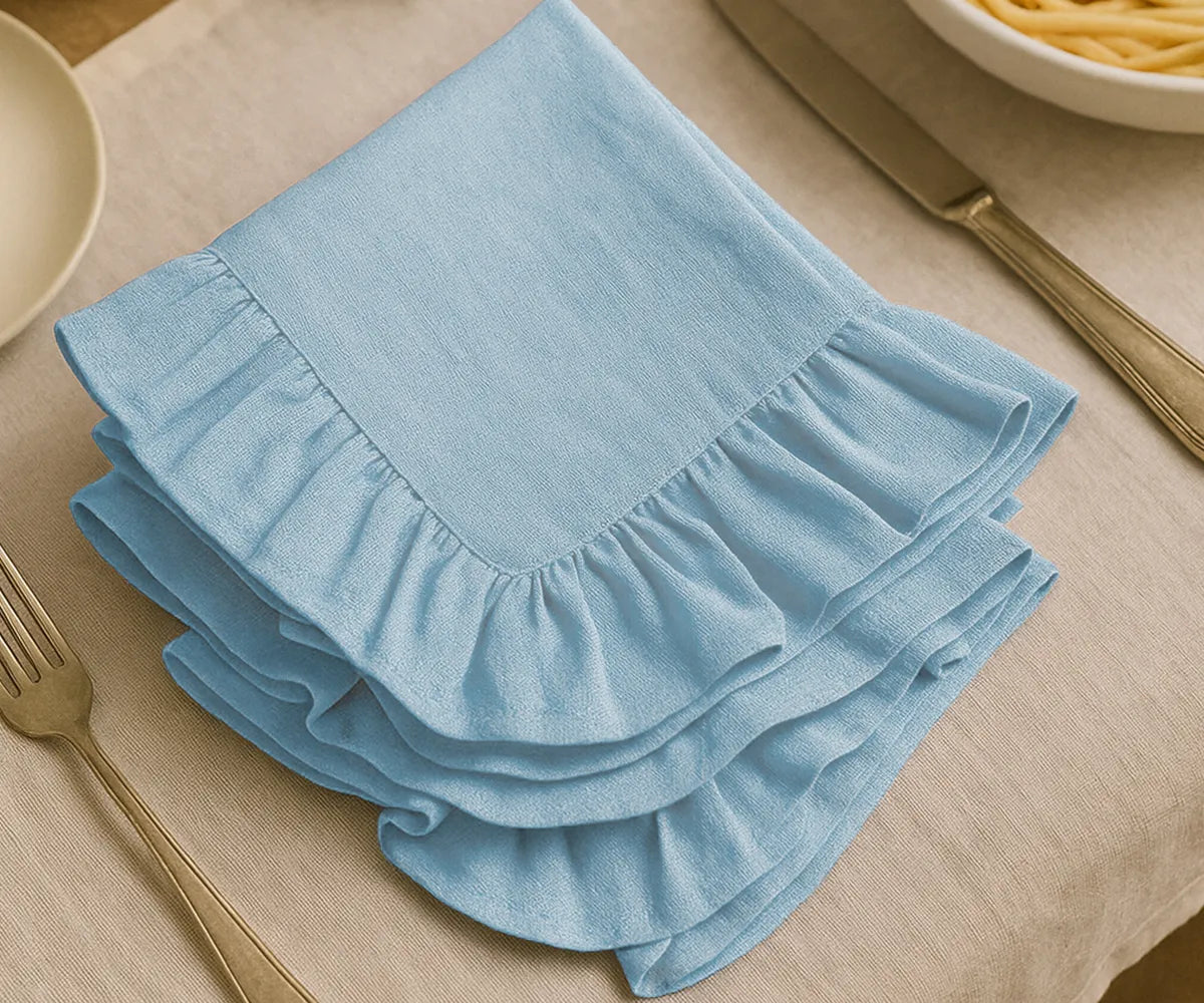 Elegant light blue fabric napkins with ruffle edging, arranged for baby showers and party table decor. These cotton napkins offer a gentle color tone and graceful design, perfect for hosting celebrations, special occasions, and seasonal gatherings with a coordinated table setting.