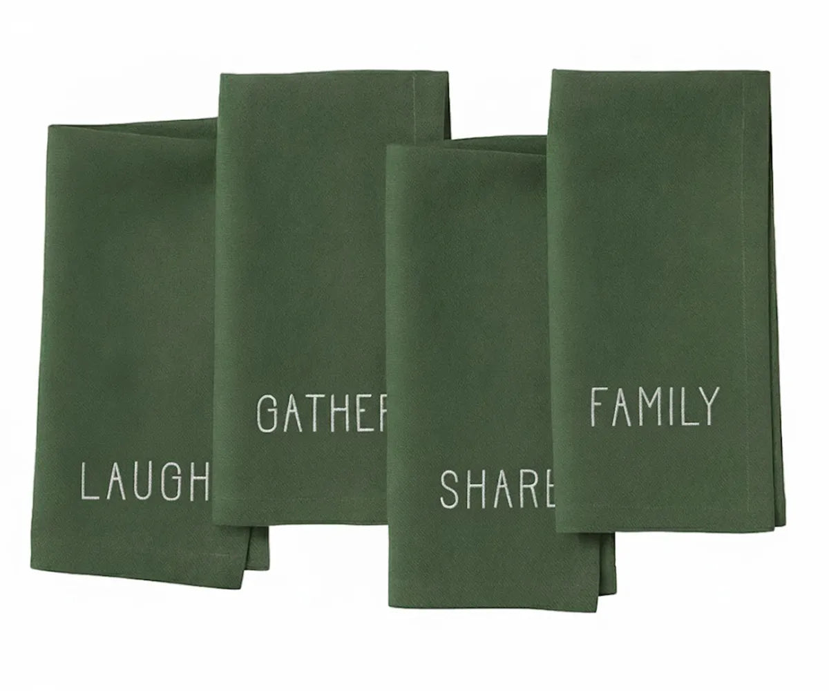 Light green cotton napkin with delicate white embroidery reading “Laugh, Family, Share, Gather” — soft farmhouse style.
