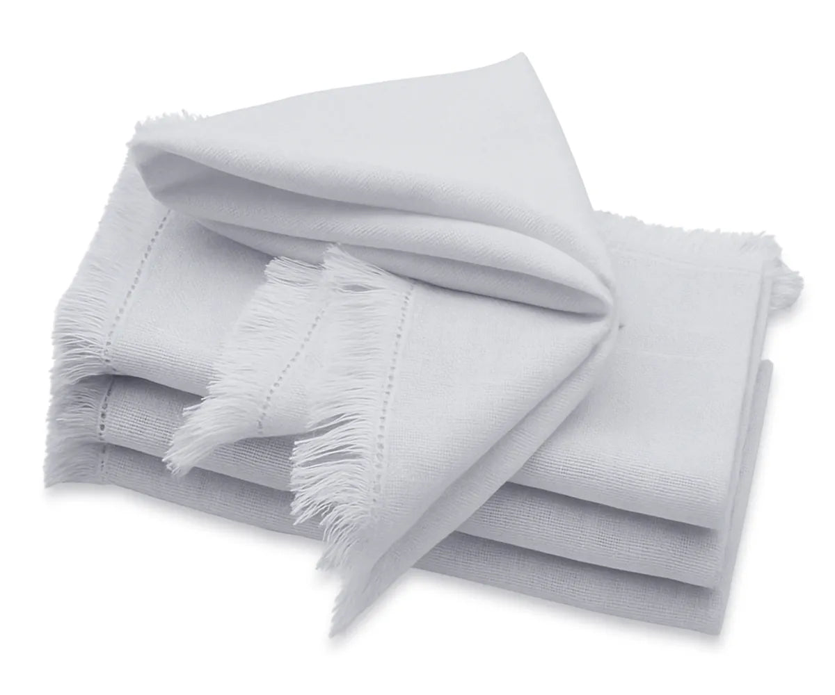 Light grey cotton napkins with frayed edge and fringe trim on dining table