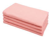 Light pink cotton cloth dinner napkin neatly folded on a dining table.