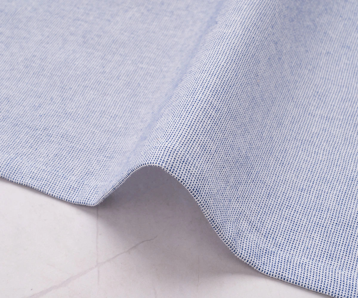 Soft light blue fabric napkin paired with silver cutlery and white dinnerware.