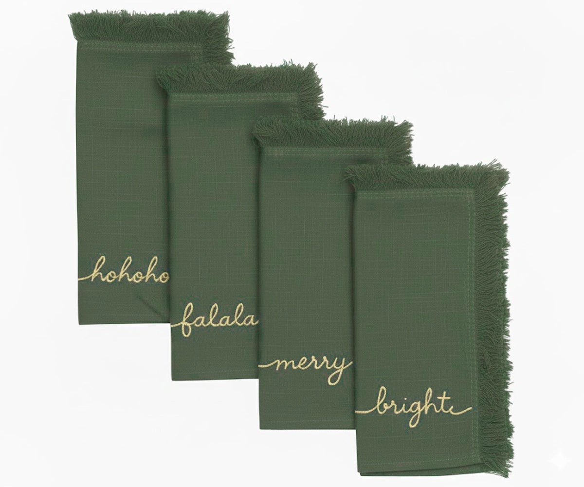 Light green embroidered napkins with gold holiday words and fringed edges for elegant Christmas dining