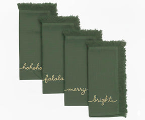 Light green embroidered napkins with gold holiday words and fringed edges for elegant Christmas dining