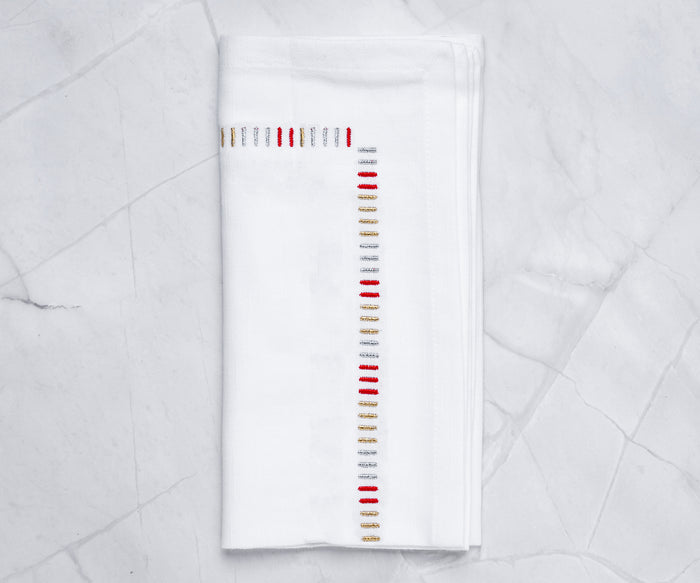 White cotton cloth napkins with gold embroidered edge – set of 4 on dining table