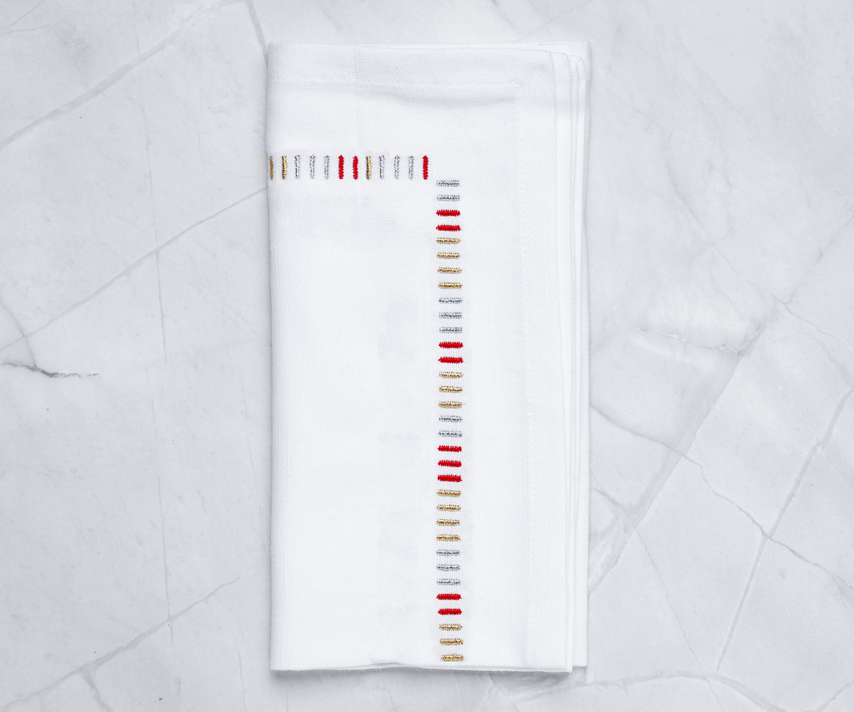 White cotton cloth napkins with gold embroidered edge – set of 4 on dining table