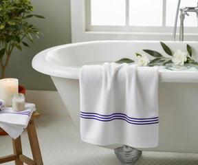 Premium cotton bath towel featuring a white base with royal blue stripe detailing, breathable, gentle on skin, and perfect for luxurious everyday bathing.