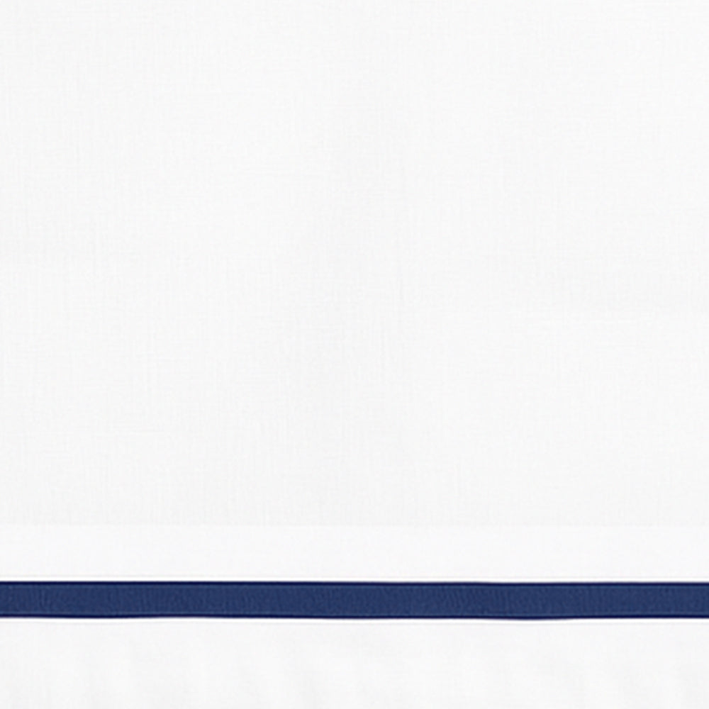 Close-up detail of white linen pillowcase with a navy blue embroidered border line.