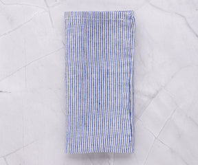 Blue and white linen striped napkin laid out on a marble background