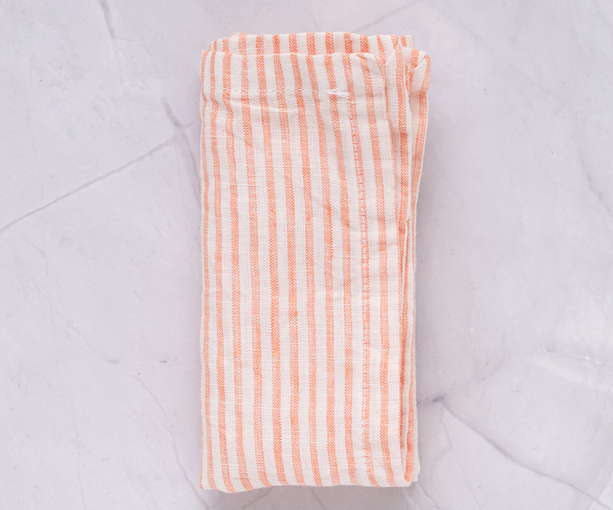 An orange and white striped linen napkin placed on a marble background