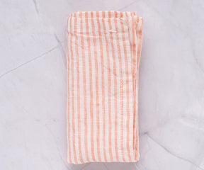 An orange and white striped linen napkin placed on a marble background